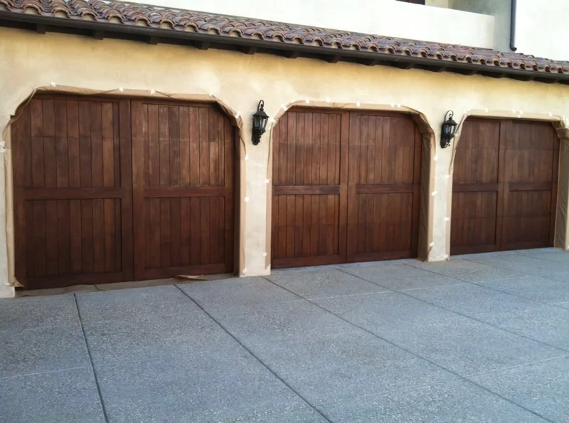 Tres puertas de garaje de madera con arcos en una casa de estuco